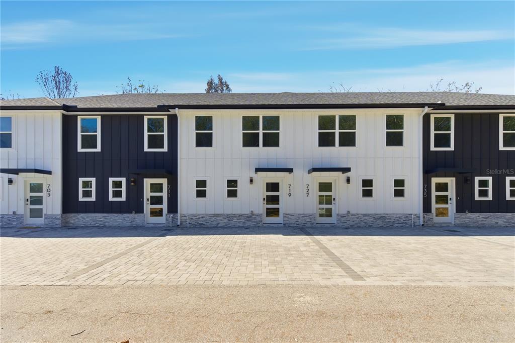A row of modern townhomes features white and dark blue siding with stone base accents — 719 CLEMSON DRIVE, ALTAMONTE SPRINGS, FL