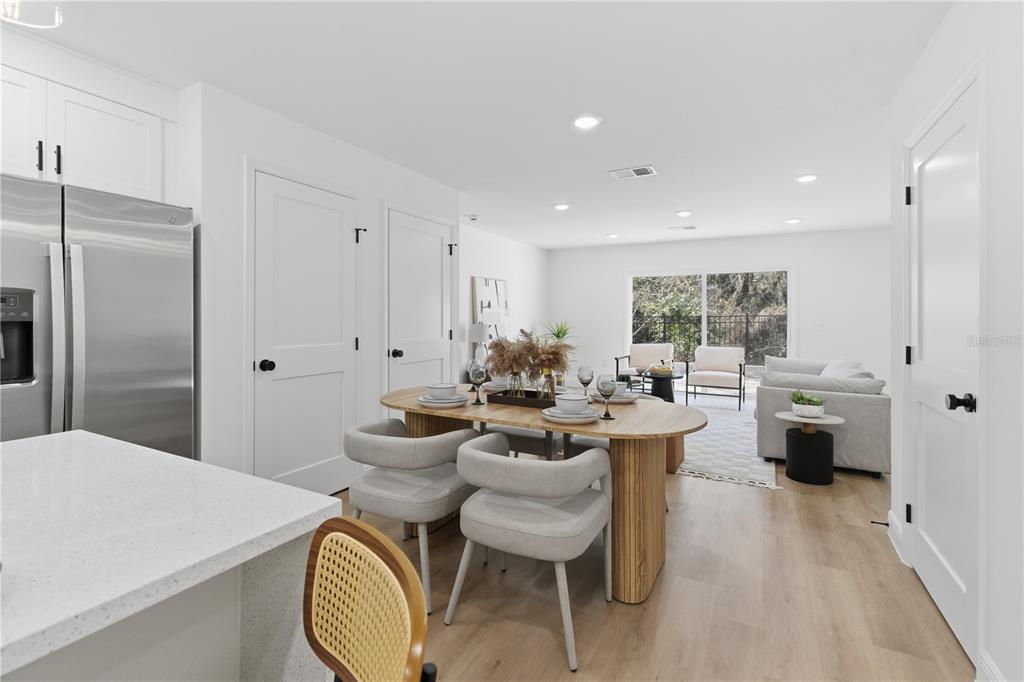 A modern open-concept kitchen and dining area with light wood floors and white cabinetry — 719 CLEMSON DRIVE, ALTAMONTE SPRINGS, FL