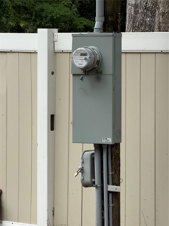 An electrical meter and service panel are mounted on a wooden post against a fence — 11259 NE 10TH TERRACE, OXFORD, FL