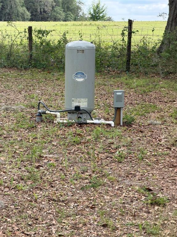A gray Challenger well pressure tank sits outdoors on a dirt lot near a fence — 11259 NE 10TH TERRACE, OXFORD, FL