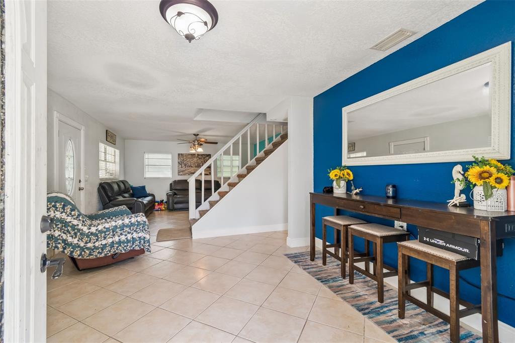 A living room features tile flooring, a staircase, and a blue accent wall with a mirror — 18632 ROSEMARY ROAD, ARIPEKA, FL