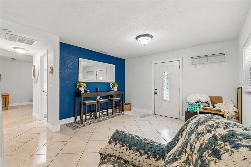 An entryway features a blue accent wall, a console table with stools, and tiled flooring — 18632 ROSEMARY ROAD, ARIPEKA, FL