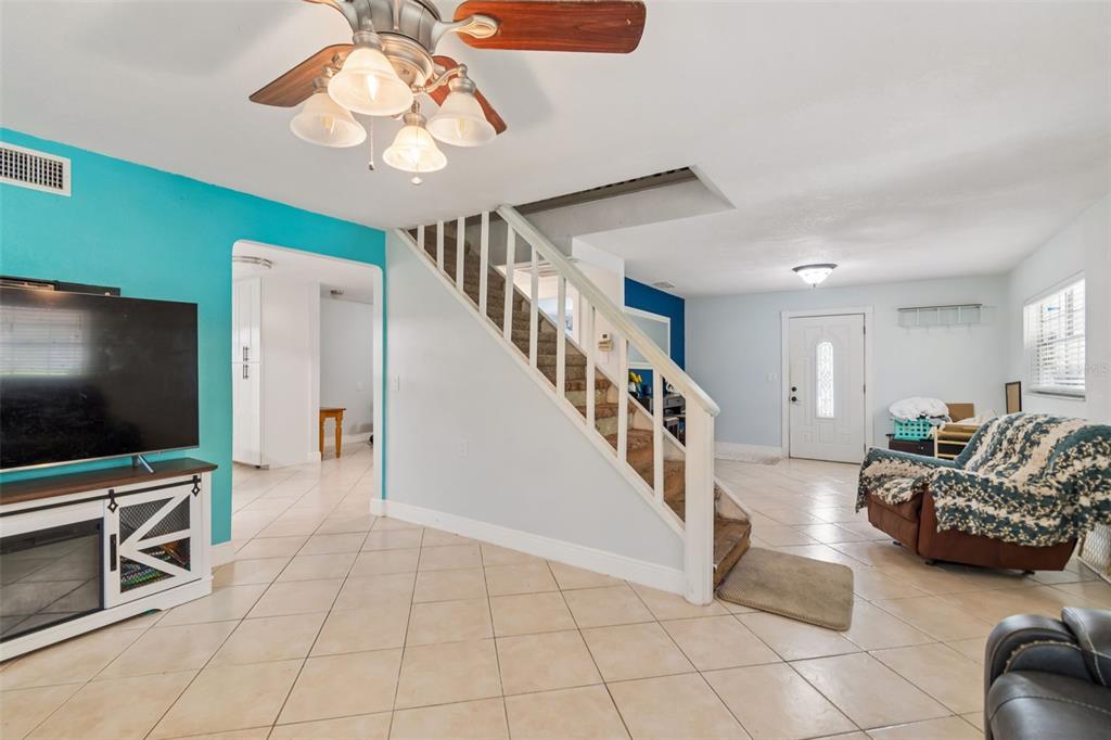 A living room features tile flooring, a staircase with white railings, and a ceiling fan — 18632 ROSEMARY ROAD, ARIPEKA, FL