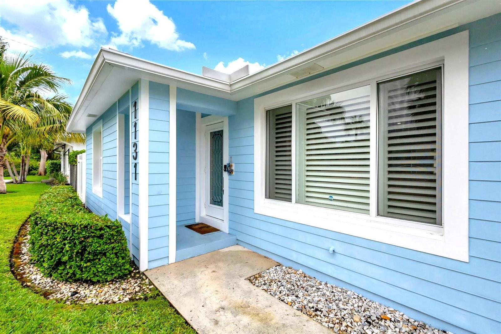 A light blue house exterior features a front door, a large window, and house numbers — 1131 Surf Road, Singer Island FL 33404, SINGER ISLAND, FL