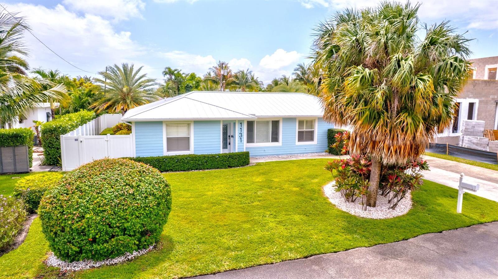 A light blue single-story house with a white metal roof and a manicured front lawn — 1131 Surf Road, Singer Island FL 33404, SINGER ISLAND, FL