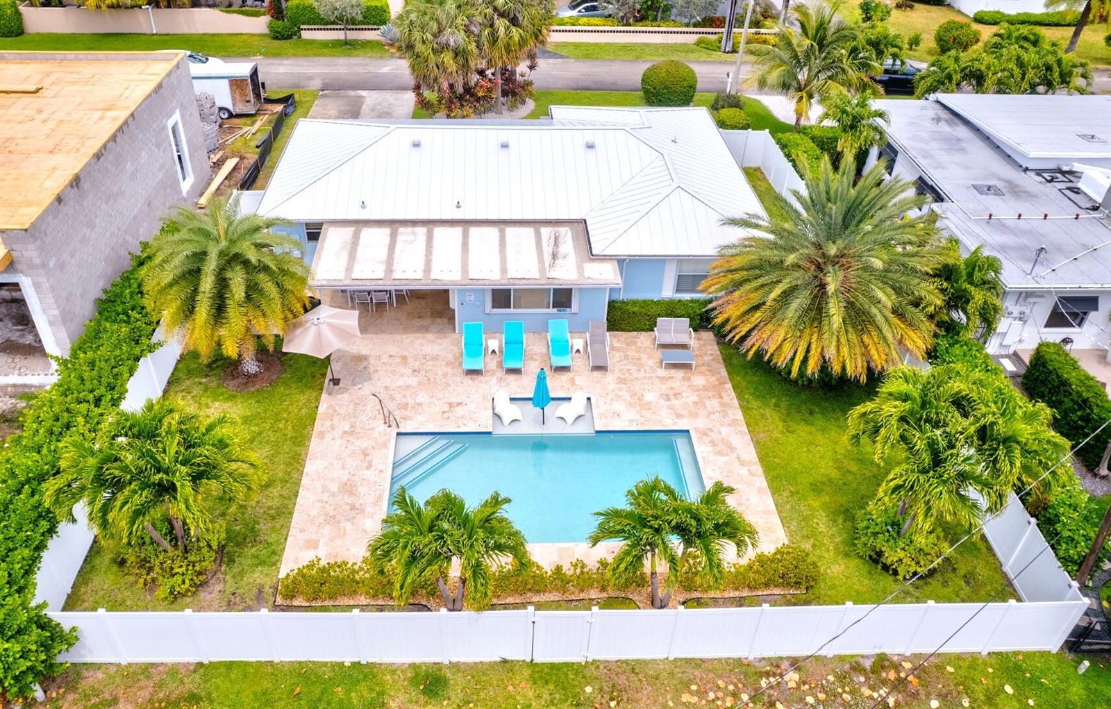 An aerial view shows a house with a metal roof, a pool, and palm trees — 1131 Surf Road, Singer Island FL 33404, SINGER ISLAND, FL