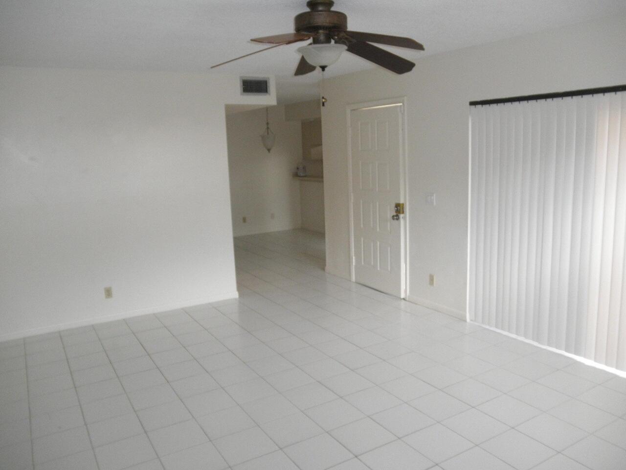 An empty room with white tile flooring, a ceiling fan, and a sliding glass door — WEST PALM BEACH, FL