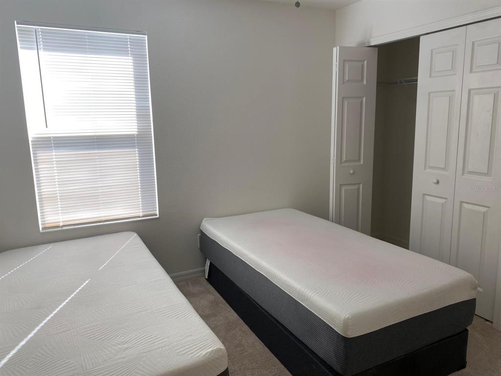 A bedroom features two twin beds, a window with blinds, and a white closet — 258 ANNABELLE WAY, DAVENPORT, FL