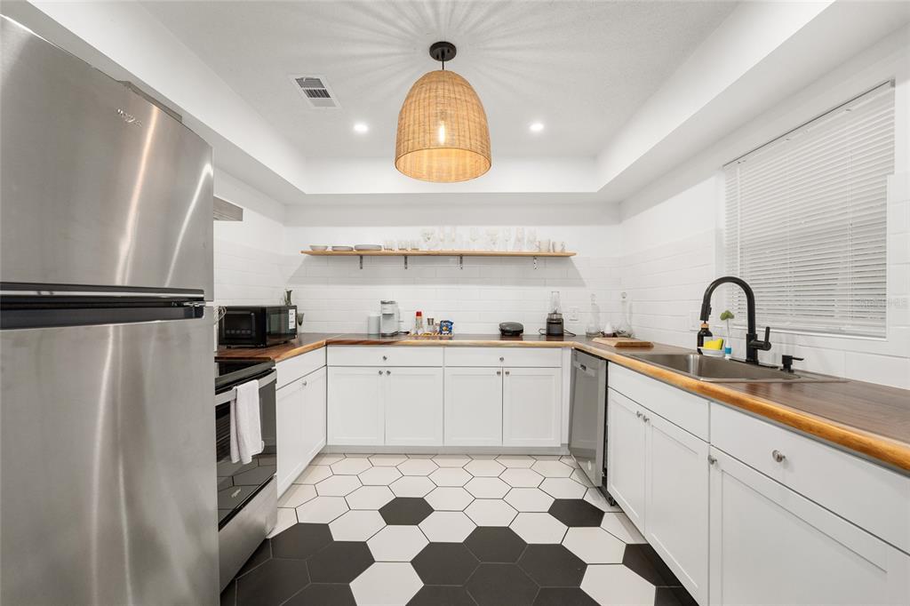 A kitchen with white cabinets, wood countertops, black and white hexagonal floor tiles, and pendant lighting — 1214 NW 55TH TERRACE, GAINESVILLE, FL
