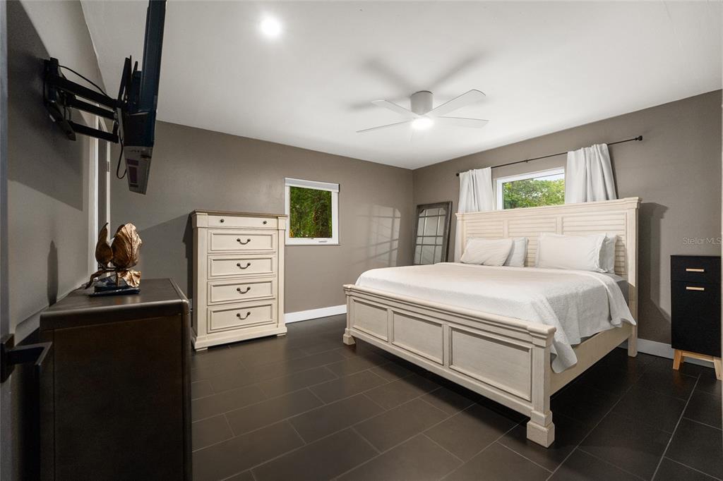 A bedroom features a white bed frame, a tall dresser, and dark tile flooring — 1214 NW 55TH TERRACE, GAINESVILLE, FL