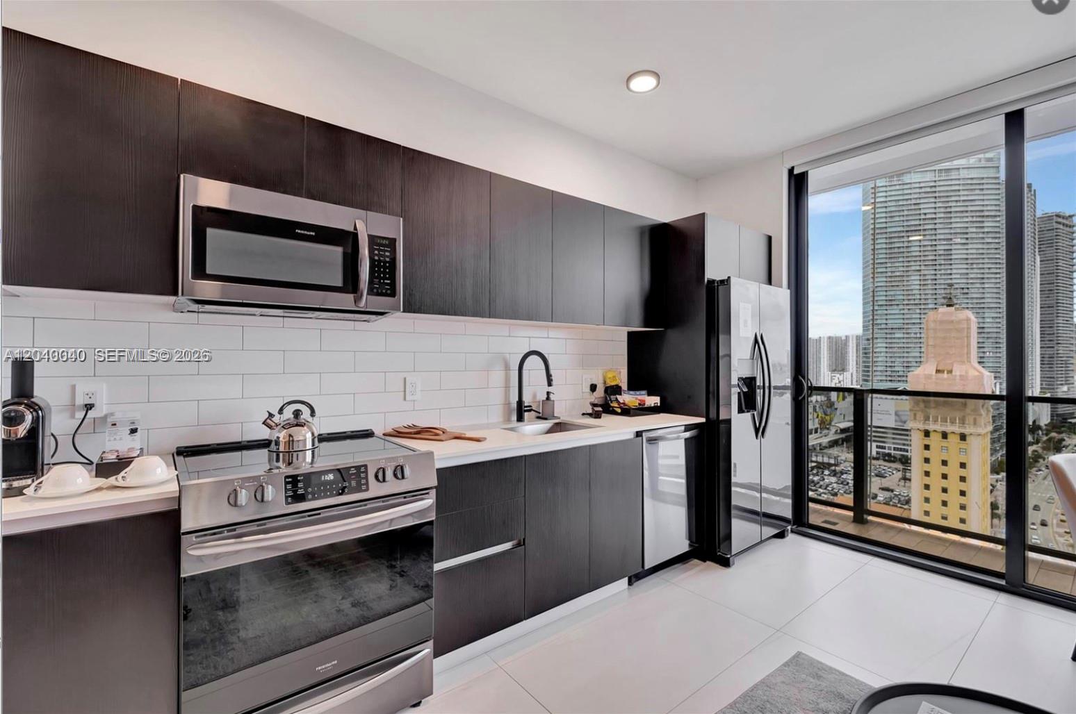 A modern kitchen features dark wood cabinetry, stainless steel appliances, and a view of skyscrapers — 398 NE 5th St, Miami FL 33132, MIAMI, FL