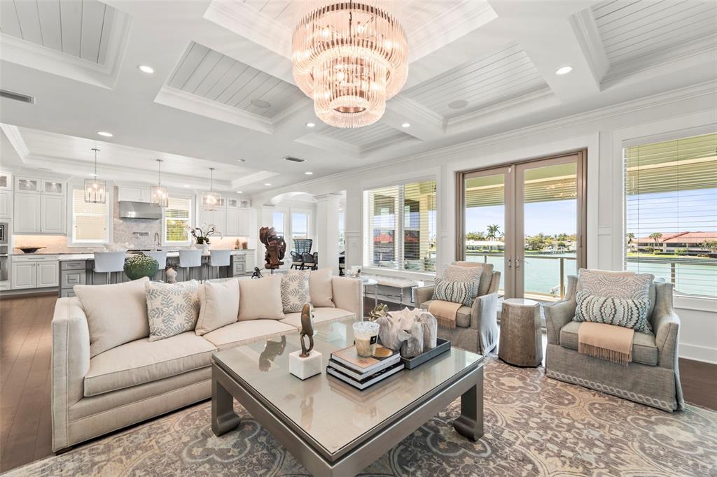 A bright living room features a coffered ceiling, crystal chandelier, and views of the water — 19 BAYFRONT COURT S, ST PETERSBURG, FL
