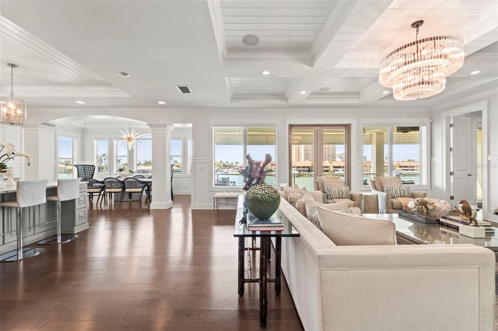 A bright, open-concept living and dining area features coffered ceilings, hardwood floors, and waterfront views — 19 BAYFRONT COURT S, ST PETERSBURG, FL
