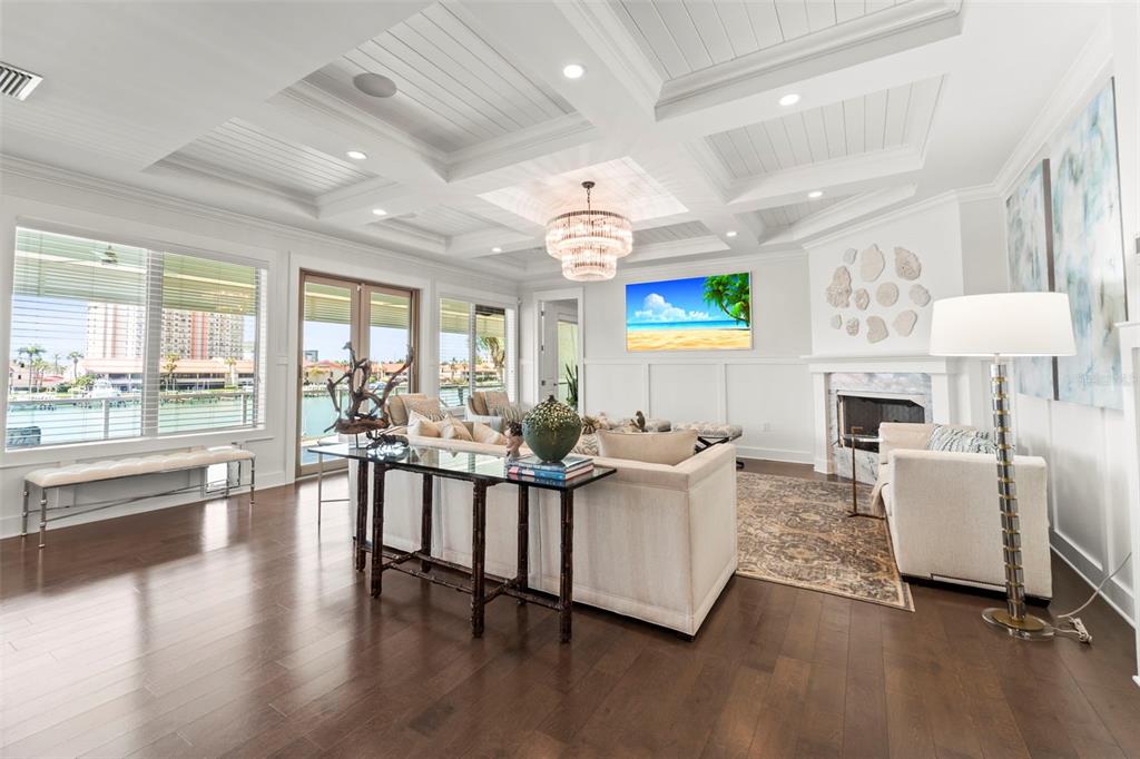 A bright living room features a coffered ceiling, fireplace, and large windows overlooking the water — 19 BAYFRONT COURT S, ST PETERSBURG, FL