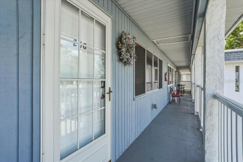 A covered exterior walkway features blue vertical siding, a white storm door, and a wreath — 22375 EDGEWATER DRIVE UNIT 256, PUNTA GORDA, FL