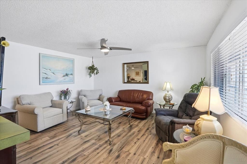 A living room features wood-look flooring, a ceiling fan, and a mix of seating furniture — 22375 EDGEWATER DRIVE UNIT 256, PUNTA GORDA, FL