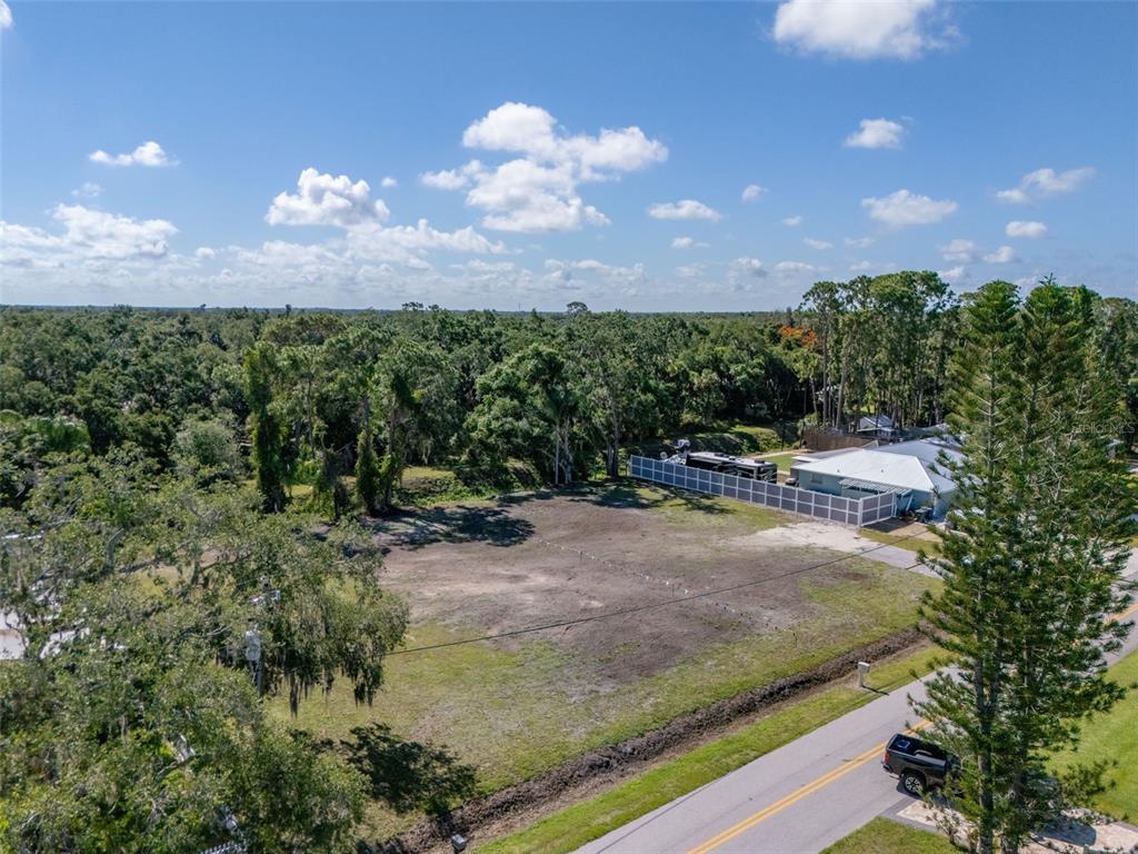 An aerial view shows a cleared, vacant residential lot next to a house and trees — 1941 E LEEWYNN DRIVE, SARASOTA, FL