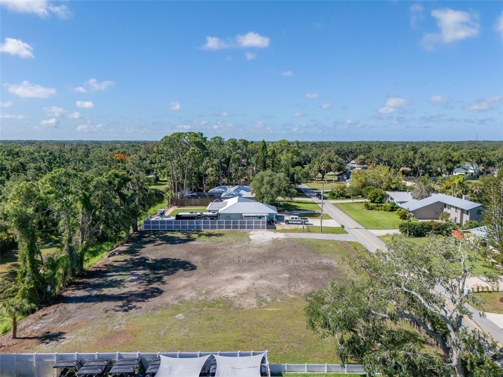 An aerial view shows a vacant, cleared residential lot next to a house and trees — 1941 E LEEWYNN DRIVE, SARASOTA, FL