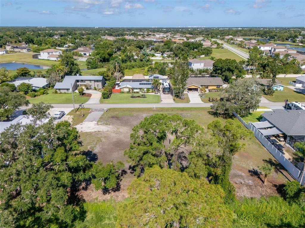 An aerial view shows a vacant, partially cleared residential lot situated across from several houses — 1941 E LEEWYNN DRIVE, SARASOTA, FL