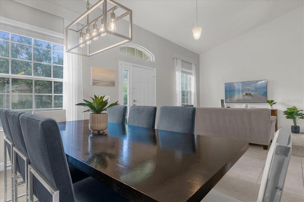 A dining area with a dark wood table and chairs sits adjacent to a living room — 4072 OAKTREE DRIVE, DAVENPORT, FL