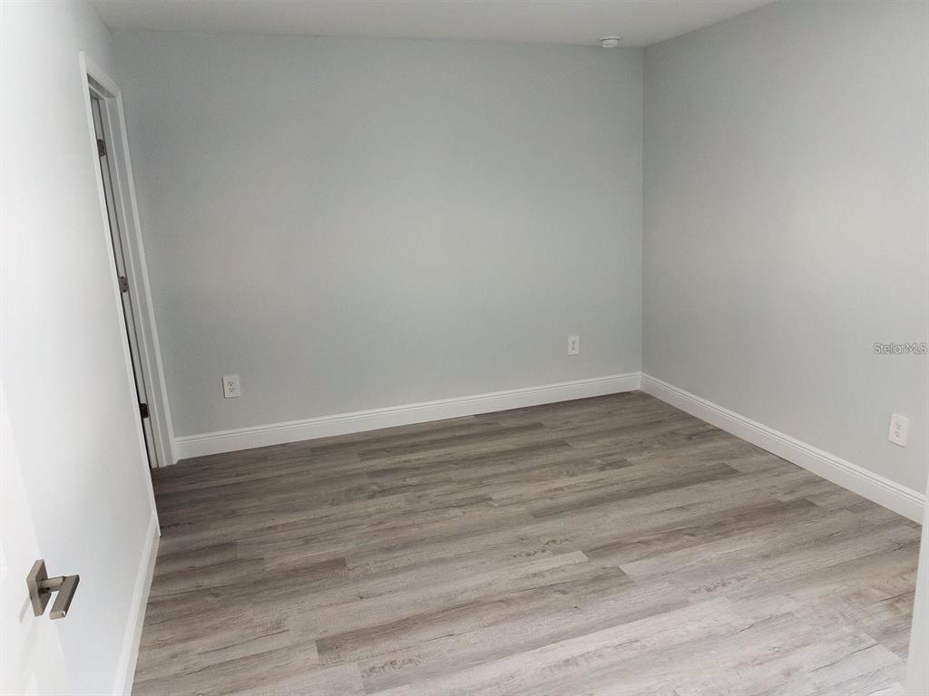 An empty room with light gray walls, white trim, and wood-look laminate flooring — 1725 CRYSTAL GROVE DRIVE UNIT 1727, LAKELAND, FL