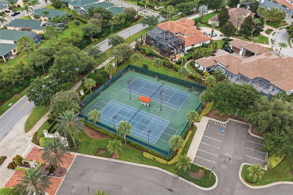 An aerial view shows two tennis courts surrounded by a fence, landscaping, and parking spaces — 10341 ALTRARA WAY, TRINITY, FL