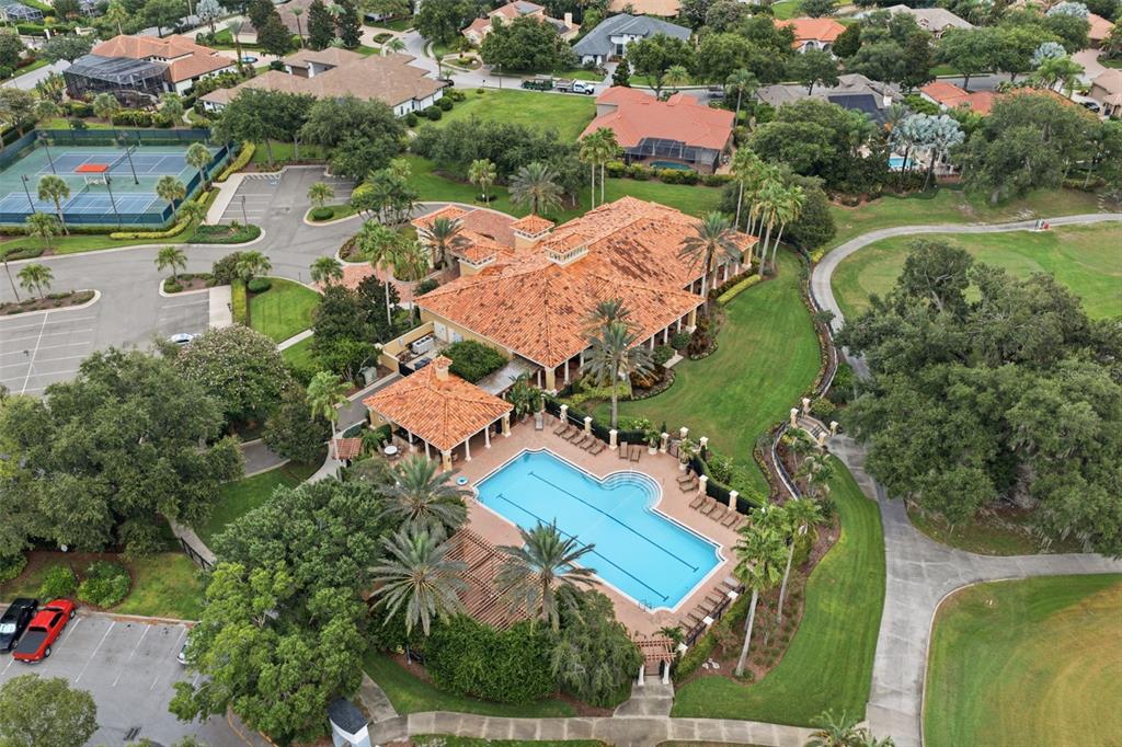 An aerial view shows a clubhouse with a tile roof, swimming pool, and tennis courts — 10341 ALTRARA WAY, TRINITY, FL