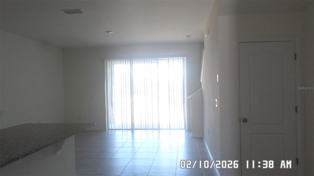 A room with tiled flooring, a granite-topped counter, and sliding glass doors with vertical blinds — 1026 LIDO DRIVE, HOWEY IN THE HILLS, FL