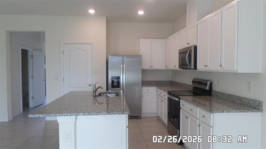A kitchen features white cabinets, granite countertops, stainless steel appliances, and a central island — 1026 LIDO DRIVE, HOWEY IN THE HILLS, FL
