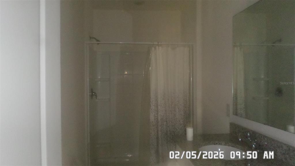 A bathroom features a walk-in shower with a curtain and a granite-topped vanity — 1026 LIDO DRIVE, HOWEY IN THE HILLS, FL