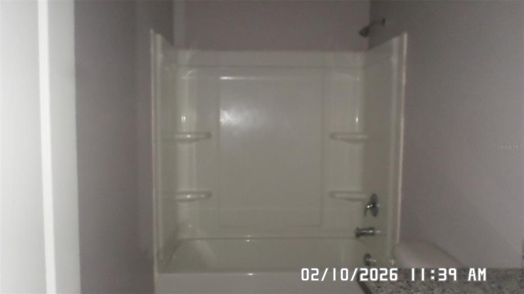 A white fiberglass bathtub and shower surround with built-in shelves and chrome fixtures — 1026 LIDO DRIVE, HOWEY IN THE HILLS, FL