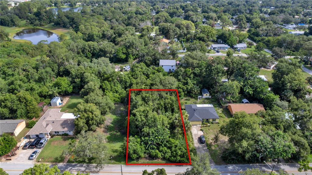 An aerial view shows a rectangular, tree-covered vacant lot outlined in red between two houses — 132 COLOMBA ROAD, DEBARY, FL
