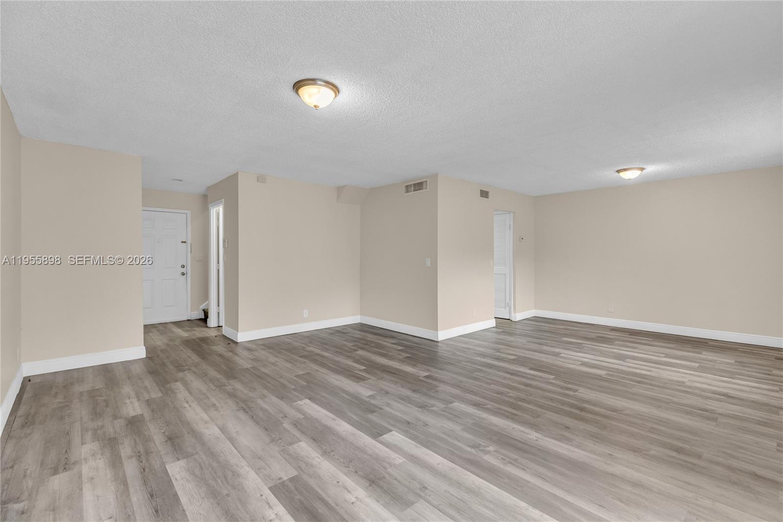 An empty room features light-colored walls, a textured ceiling, and gray wood-look flooring — 17901 NW 68th Ave # T206, Hialeah FL 33015, HIALEAH, FL