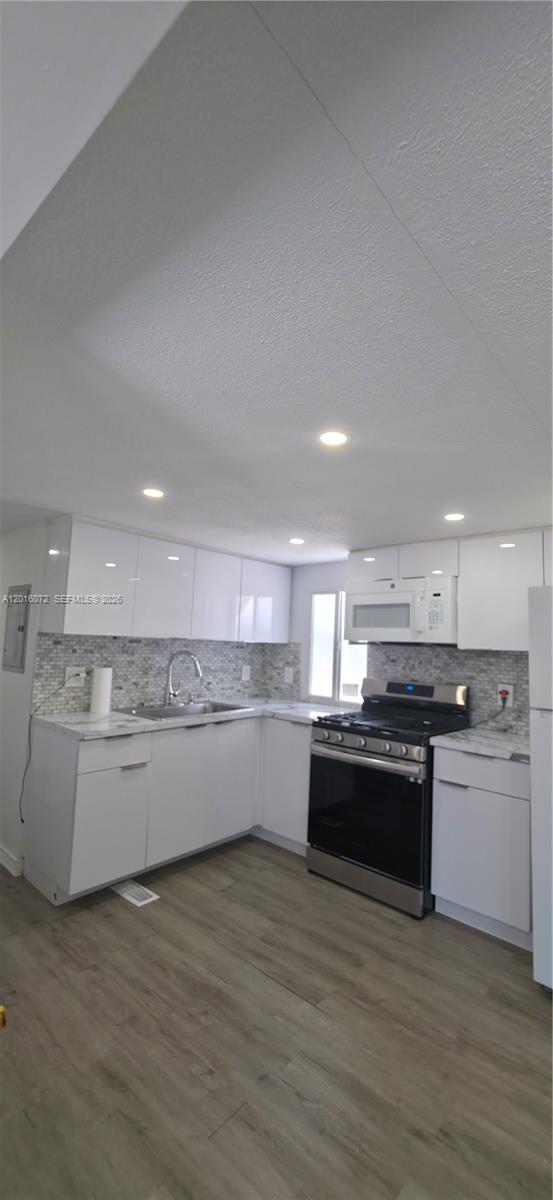 A modern kitchen features white cabinets, stainless steel appliances, and a tiled backsplash — 1730 SW 85th Ave, Davie FL 33324, DAVIE, FL