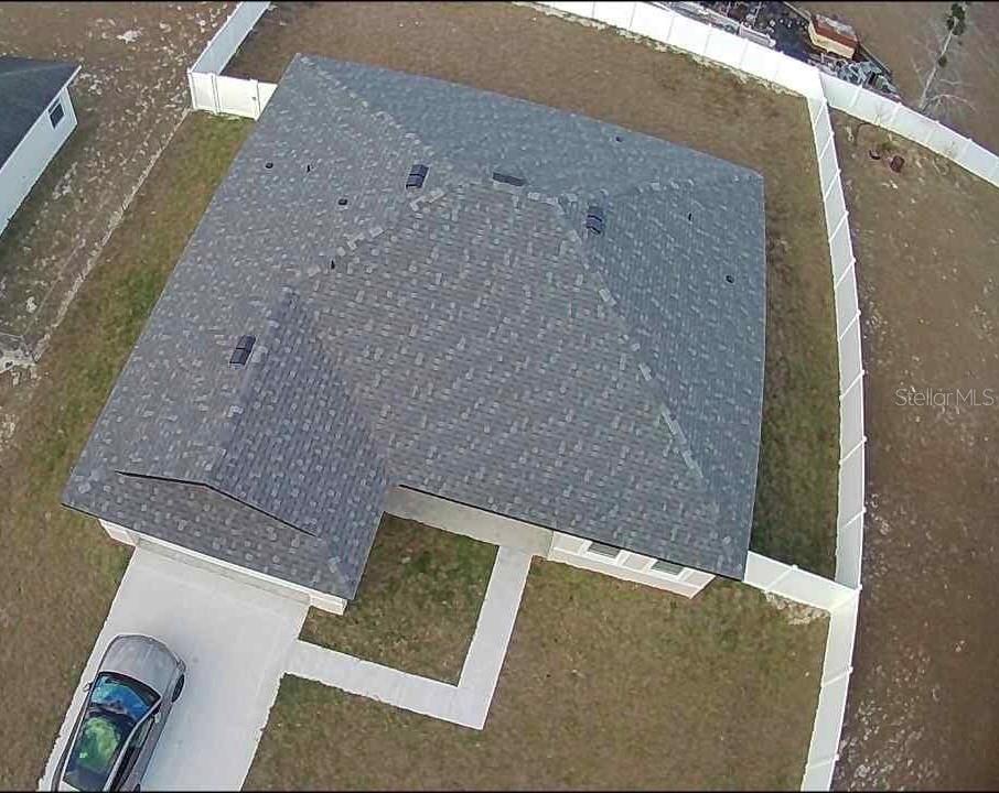 An aerial view shows a house with a gray shingled roof, driveway, and fenced yard — 723 MARION OAK TRAIL, OCALA, FL