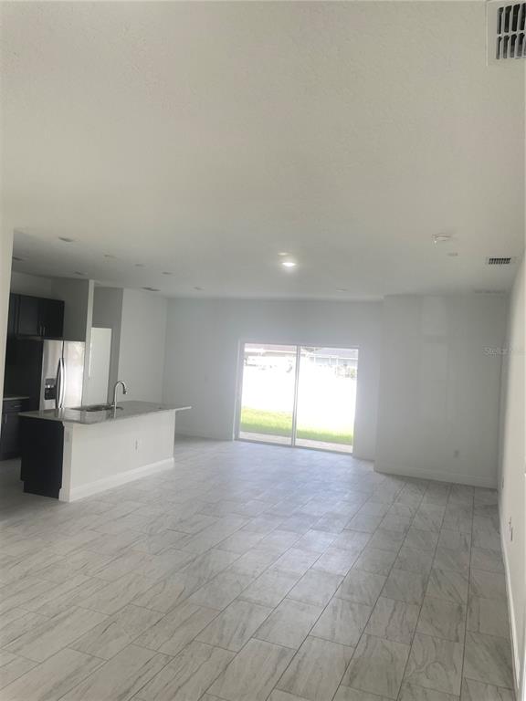 An open-concept kitchen with a breakfast bar overlooks a living area with tile flooring — 723 MARION OAK TRAIL, OCALA, FL