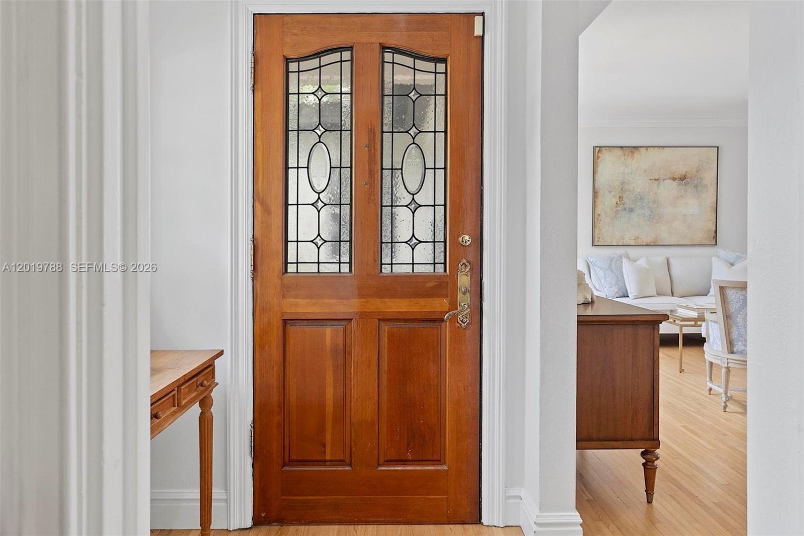 A wooden front door with leaded glass panels opens into a bright living area — 1540 Urbino Ave, Coral Gables FL 33146, CORAL GABLES, FL