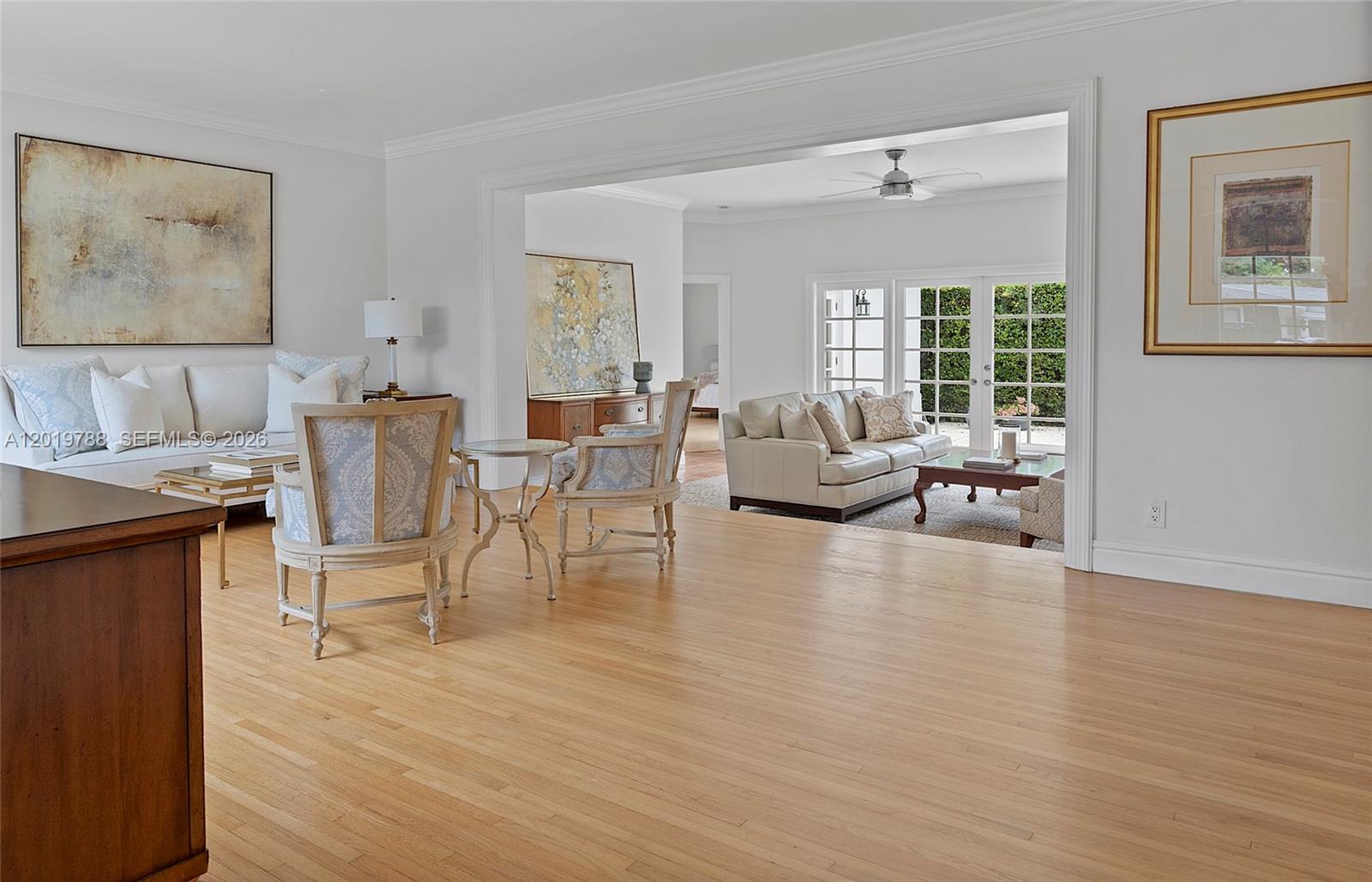A bright living area features light wood floors, white walls, and two distinct seating arrangements — 1540 Urbino Ave, Coral Gables FL 33146, CORAL GABLES, FL