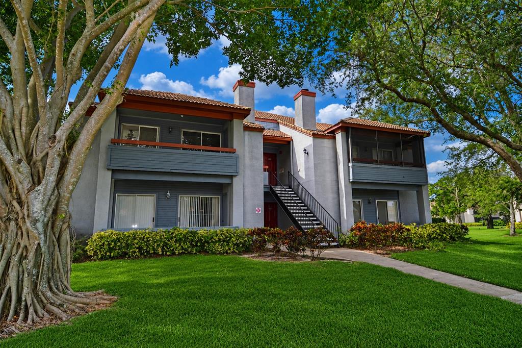 A two-story apartment building with a gray exterior, a tiled roof, and an outdoor staircase — 10263 GANDY BOULEVARD N UNIT 405, ST PETERSBURG, FL