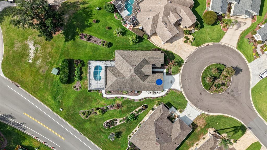 An aerial view shows a residential house with a pool, driveway, and landscaped yard — 745 DOWDING WAY, THE VILLAGES, FL