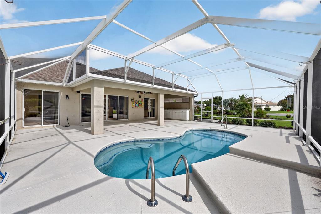 A screened-in patio features a swimming pool with a metal ladder and concrete decking — 745 DOWDING WAY, THE VILLAGES, FL