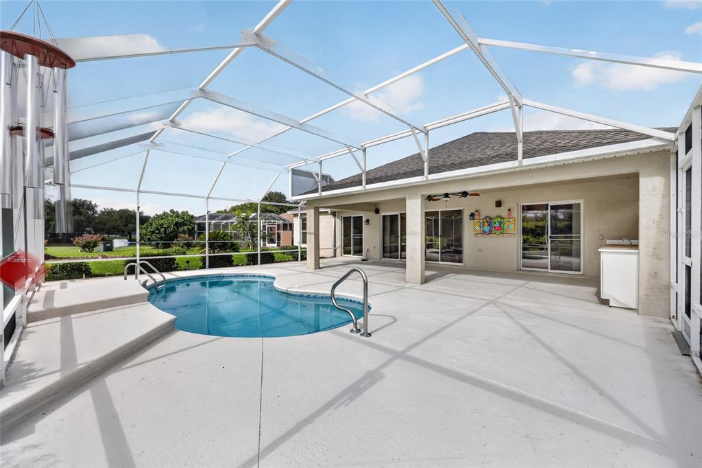A screened-in patio features a swimming pool, concrete deck, and sliding glass door access — 745 DOWDING WAY, THE VILLAGES, FL