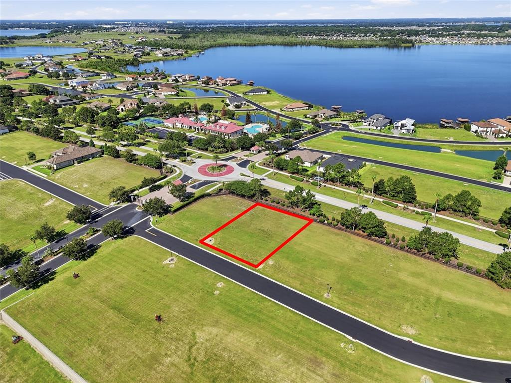 An aerial view shows a vacant rectangular residential lot outlined in red near a lake — 504 BONAMIA AVENUE, LAKE ALFRED, FL