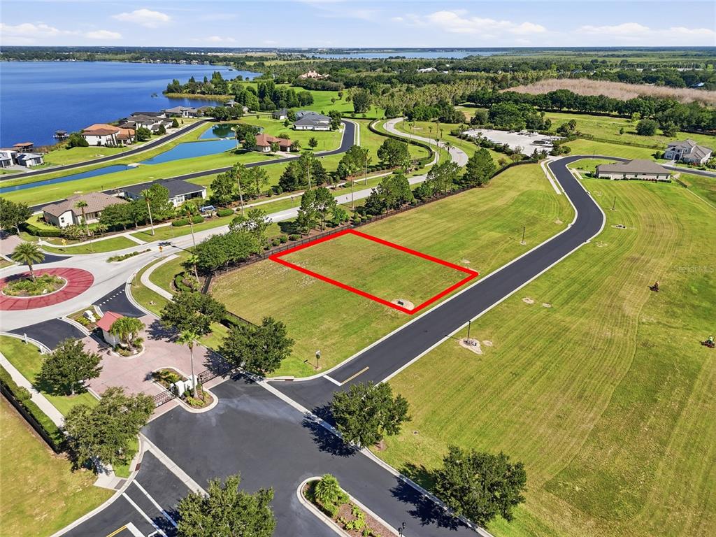 An aerial view shows a vacant rectangular residential lot outlined in red near a road — 504 BONAMIA AVENUE, LAKE ALFRED, FL