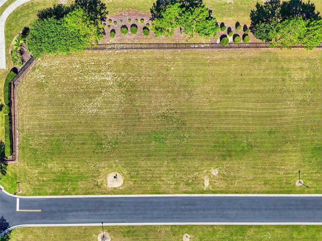 An aerial view shows a vacant, rectangular residential lot bordered by a road and trees — 504 BONAMIA AVENUE, LAKE ALFRED, FL