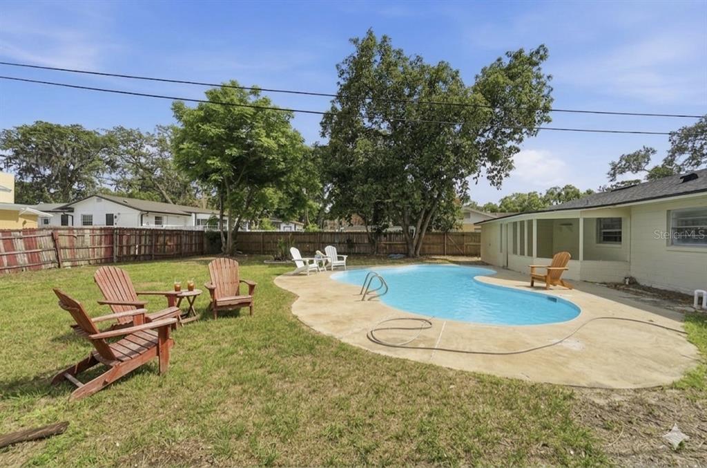 A backyard features a kidney-shaped swimming pool, a concrete patio, and several wooden chairs — 2213 VILLANO AVENUE, ORLANDO, FL