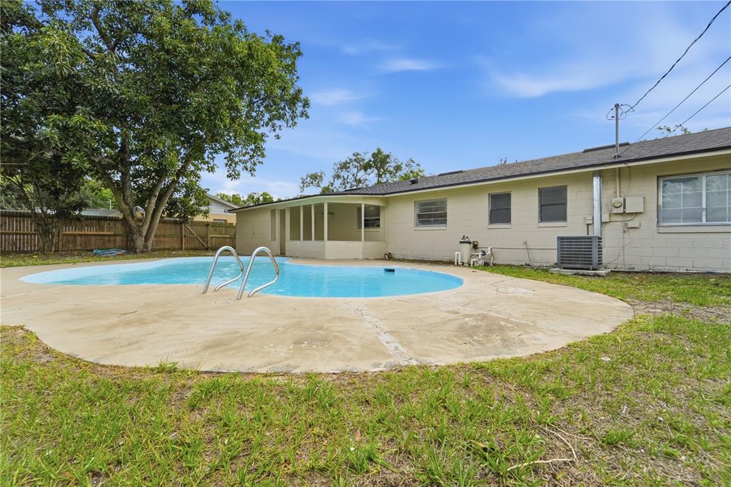 A backyard features a kidney-shaped swimming pool, a concrete patio, and a single-story house — 2213 VILLANO AVENUE, ORLANDO, FL
