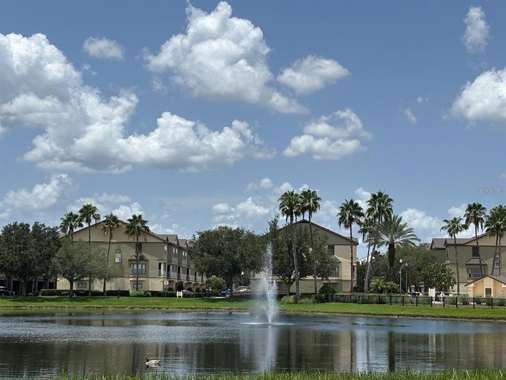 A pond with a fountain sits in front of multi-story apartment buildings and palm trees — 2424 GRAND CENTRAL PARKWAY UNIT 17, ORLANDO, FL