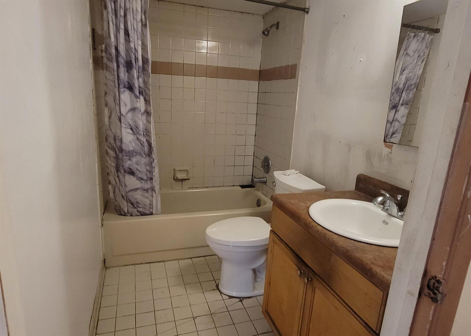A small bathroom features a tub-shower combination, a white toilet, and a wooden vanity — 1509 Meadows Circle W, Boynton Beach FL 33436, BOYNTON BEACH, FL