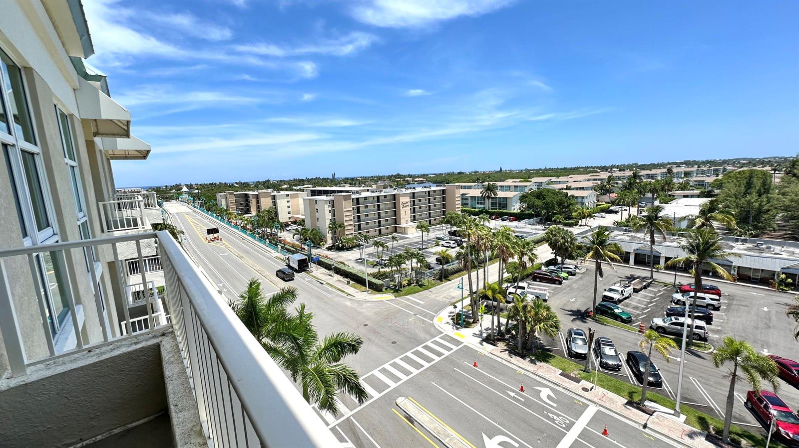 An elevated view from a balcony overlooks a street, parking lot, and apartment buildings — 100 NE 6th Street # 709, Boynton Beach FL 33435, BOYNTON BEACH, FL